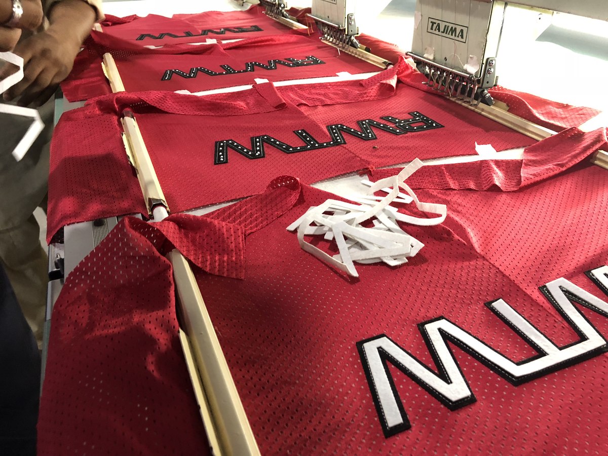 Embroidery machine stitching lettering onto a mesh jersey