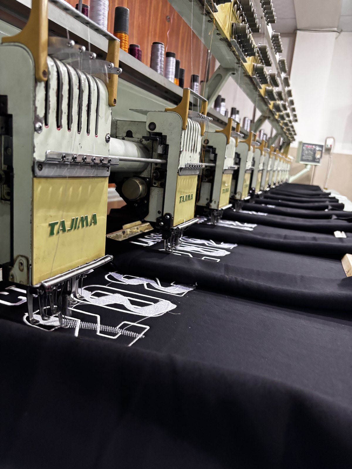 Row of multi-head embroidery machines stitching lettering