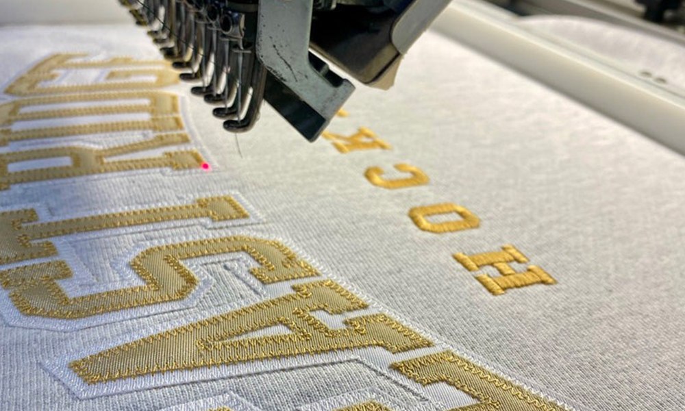 Embroidery machine stitching a gold logo
